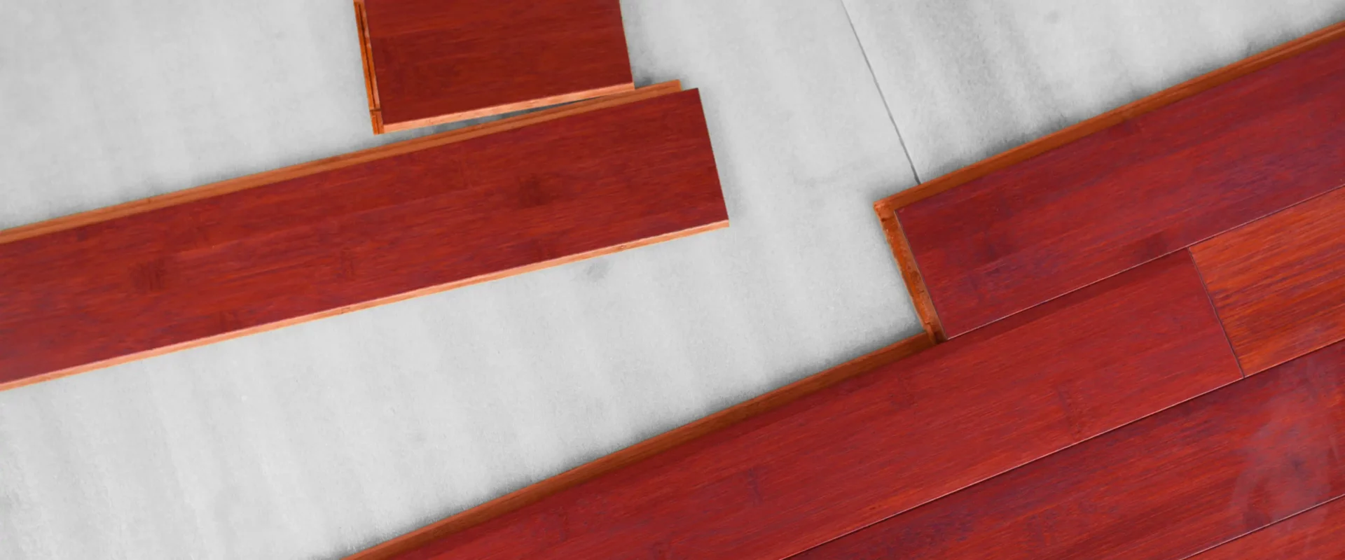 Top view of red wood floor planks being clicked together on a underlayment.