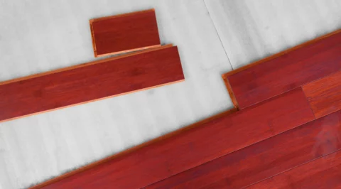 Top view of red wood floor planks being clicked together on a underlayment.