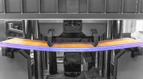 Large testing machine bending a glued laminated timber beam in a four point bending test.
