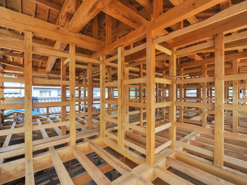 Innenansicht eines Holztragwerks im Rohbau mit Balken, Ständern und Aussteifungen.