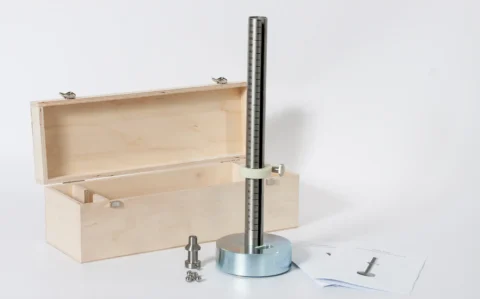 Prüfgerät für den Kleine-Kugel-Falltest: massiver runder Fuß mit vertikaler, skalierten Fallstange und Klemmring