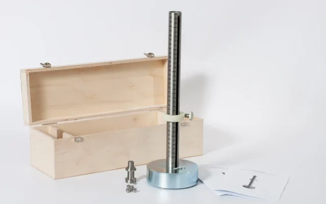 Prüfgerät für den Kleine-Kugel-Falltest: massiver runder Fuß mit vertikaler, skalierten Fallstange und Klemmring