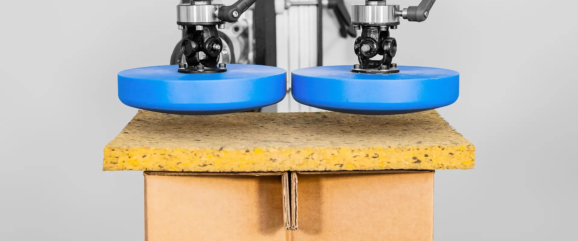 Prüfaufbau mit zwei Druckstempeln zur Belastungsprüfung einer Holzwerkstoffplatte auf Kartonunterlage