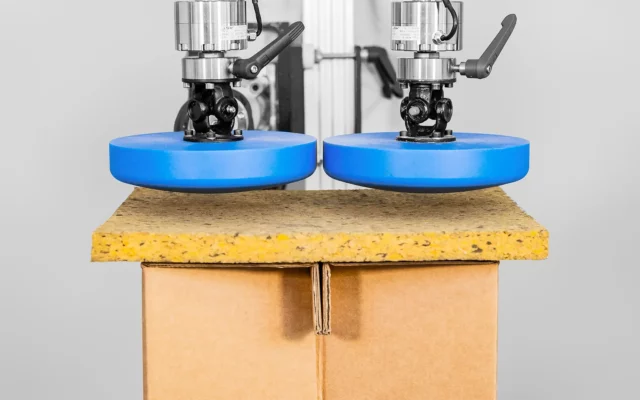 Prüfaufbau mit zwei Druckstempeln zur Belastungsprüfung einer Holzwerkstoffplatte auf Kartonunterlage